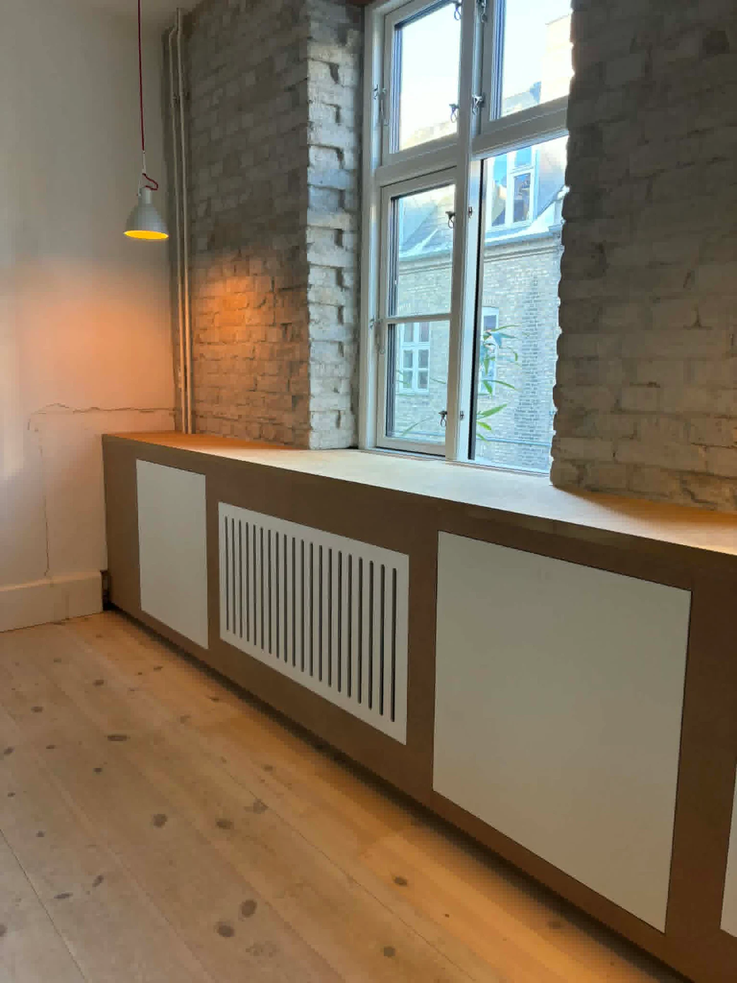 Træradiatordække under vindue i moderne indretning.