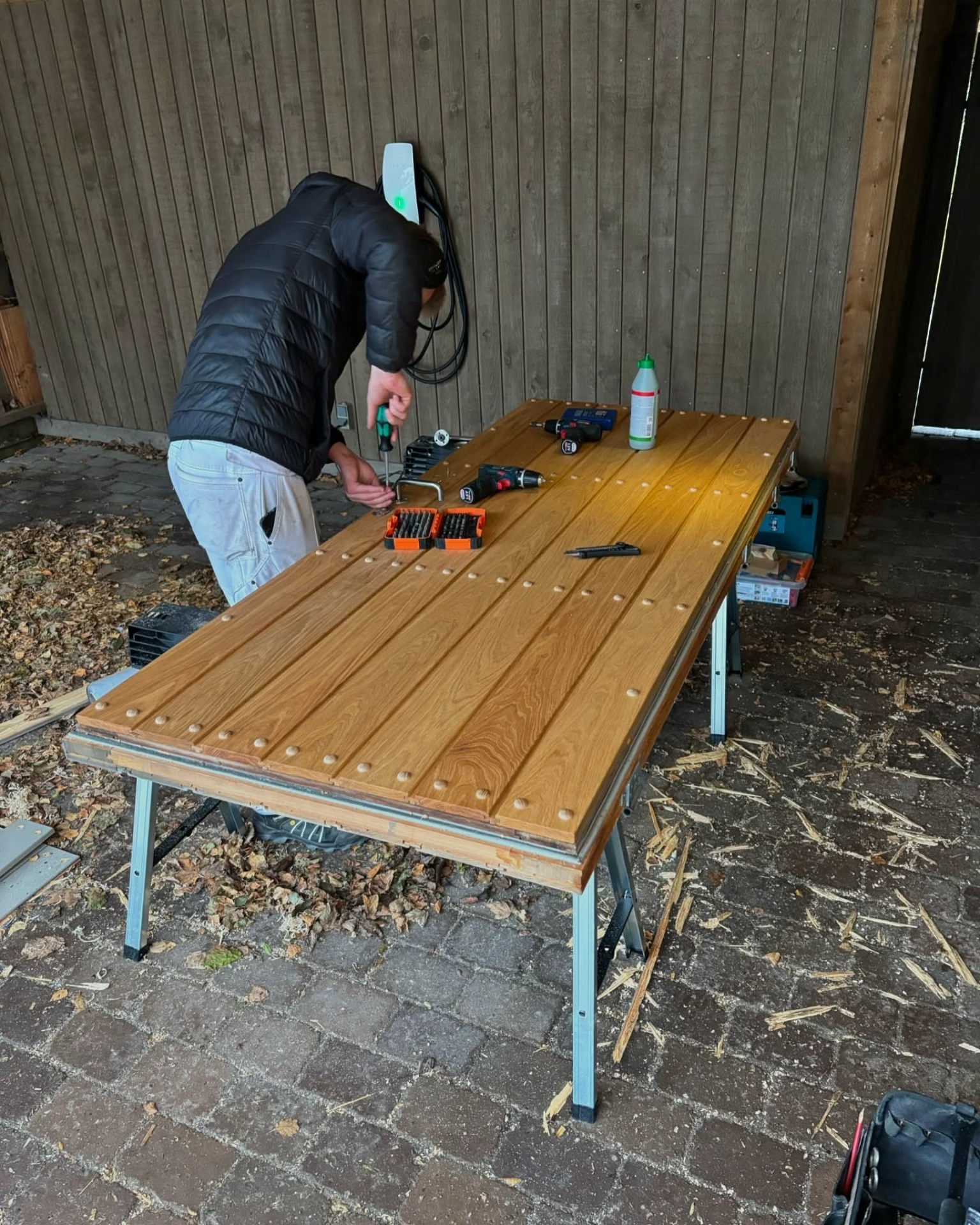 Mand arbejder med værktøj på udendørs arbejdsbord.